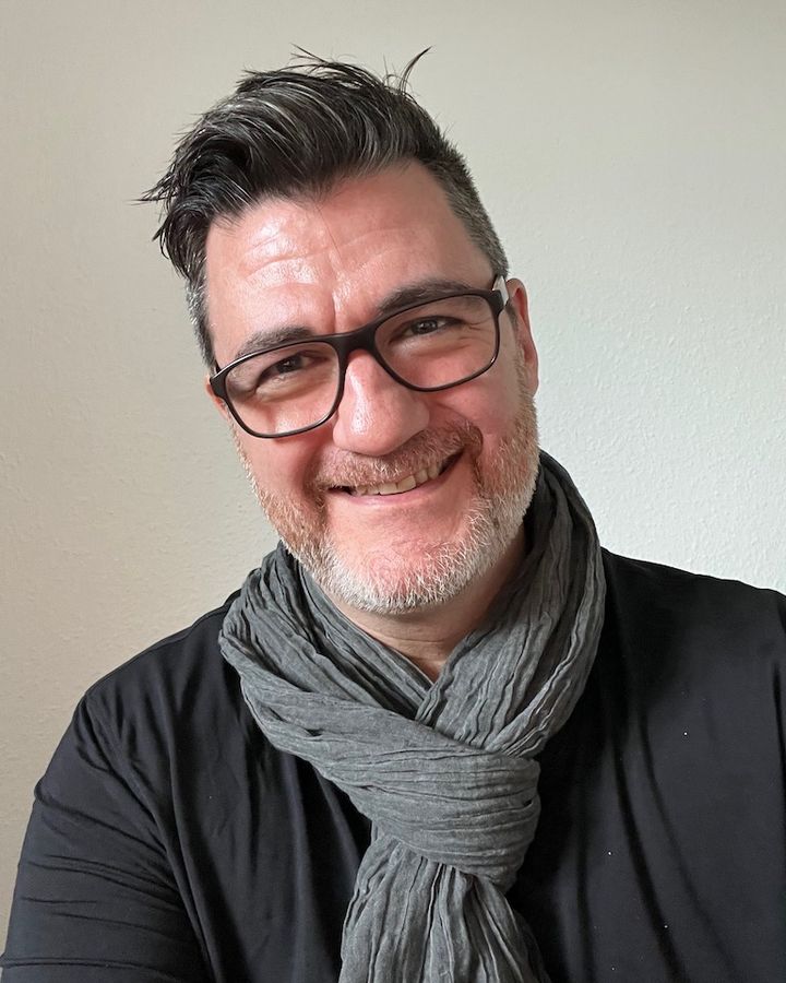 Tony Wood, smiling, in glasses and a grey scarf